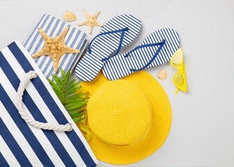 Blue beach bag with summer accessories on color background, top view