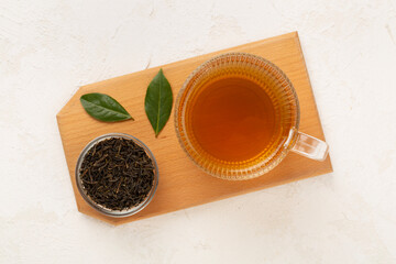 Cup of tea with dry and fresh leaves on concrete background, top view