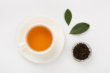 Cup of tea with dry and fresh leaves on color background, top view