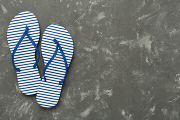 Striped blue flip flops on concrete background, top view
