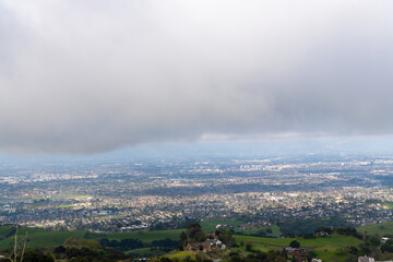 Overcast view of a city from a green hillside.