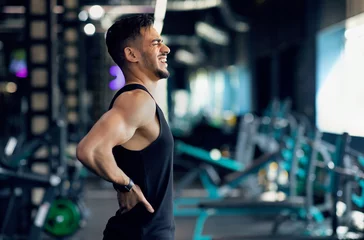 Fotobehang Sport Trauma. Young Arab Male Athlete Suffering Lower Back Pain During Training At Gym, Middle Eastern Sportsman Massaging Sore Zone And Screaming With Ache, Having Injured Lumbar Spine, Copy Space © Prostock-studio