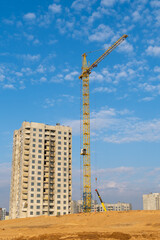 Construction of a multi-storey building with a crane against the blue sky.