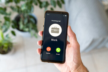 Hand holding smartphone while receiving incoming call from work.