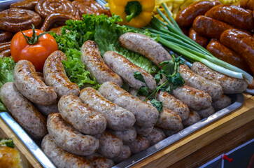 Assorted of grilled sausages arranged on platter, garnished with fresh vegetables like lettuce, tomato, and green onions, creating appetizing presentation perfect for food festivals or street markets