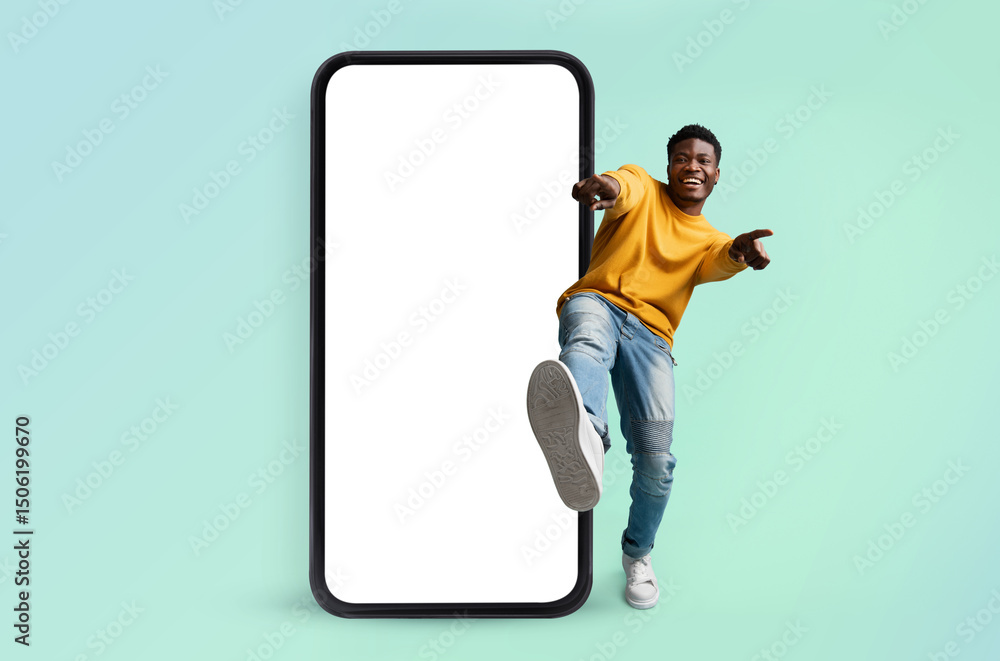 Poster hey you, check this website. excited black man standing near huge smartphone with blank screen, poin