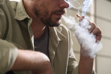 Man smoking cigarette on blurred background, closeup
