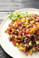 Tasty salad with brown rice on black wooden table, closeup