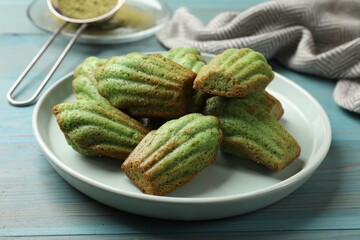 Tasty matcha madeleine cakes on light blue wooden table, closeup