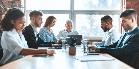 Serious Business People Working Having Meeting Sitting Together At One Table In Modern Office. Panorama, Selective Focus