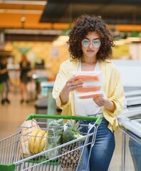 Customer choosing frozen salmon in supermarket refrigerator section