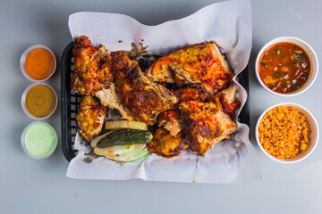 A mouth-watering plate of grilled chicken served alongside aromatic rice, spicy sauces, and grilled vegetables, showcasing a delicious blend of flavors and textures.