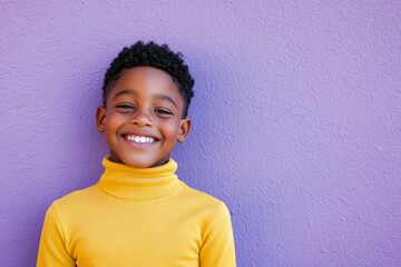 Fototapeta na wymiar Young boy smiles brightly against a purple wall, showcasing joy and innocence