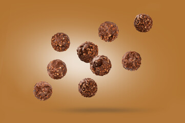 Chocolate balls candy with nuts falling on light brown background.
