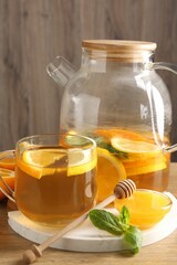 Aromatic fruit tea with orange, lemon, honey and mint on wooden table, closeup