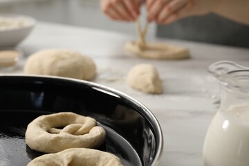 Woman shaping pretzels at table in kitchen, selective focus