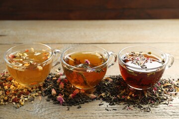 Different herbal teas and dry leaves on wooden table