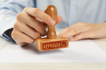 Approved. Woman stamping blank sheet of paper at table, closeup