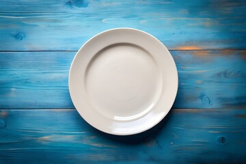 Clean white plate resting on rustic blue wooden table offering simple elegant backdrop for food presentation or minimalist design