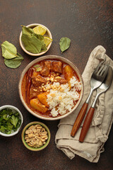 Steaming bowl of massaman curry with beef, potatoes, and coconut milk sauce, served with rice and peanuts, a traditional flavorful thai meal