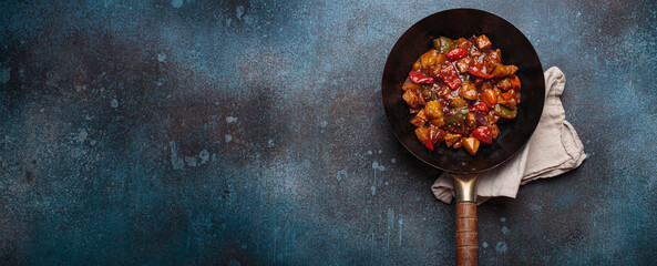 Sweet and sour pork in a wok with colorful bell peppers and pineapple chunks top view, classic Asian dish