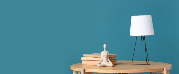 Coffee table with books, figurine and desk lamp near blue wall
