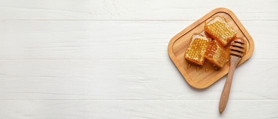 Board with honey combs on white wooden background