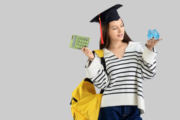 Young woman with savings for education and calculator on grey background