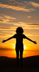 Fototapeta premium Silhouette of a Person with Open Arms Facing the Sunset