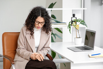 Young businesswoman suffering from pain in wrist at office