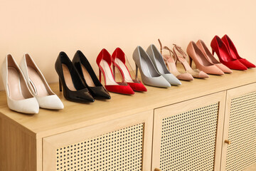 Stylish high heels on commode near beige wall