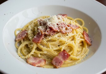 Close up view of a plate with pasta, cheese, and meat, presented beautifully