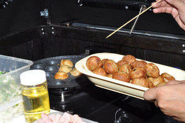 the process of cooking takoyaki on a baking pan