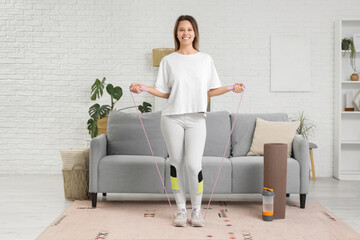 Sporty young woman with skipping rope training at home