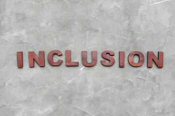 Word INCLUSION made of wooden letters on grey grunge background