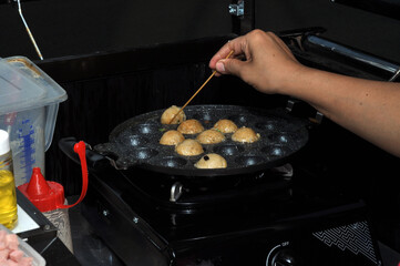 the process of cooking takoyaki on a baking pan