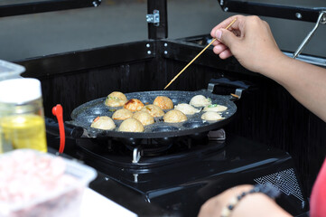 the process of cooking takoyaki on a baking pan