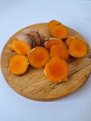 Fresh turmeric slices on a serving board. Turmeric is often used in traditional medicine and also in cooking as a flavoring and natural coloring