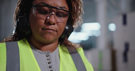 Female industrial worker wearing safety equipment concentrated taking notes on a clipboard. - Powered by Adobe