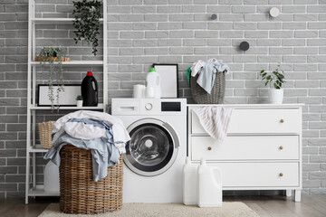 Interior of stylish bathroom with washing machine, laundry basket and dresser