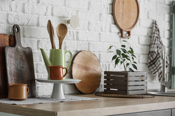 Different utensils on counter near white brick wall in kitchen
