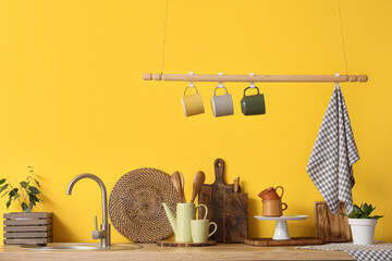 Counters with sink and utensils near yellow wall in kitchen