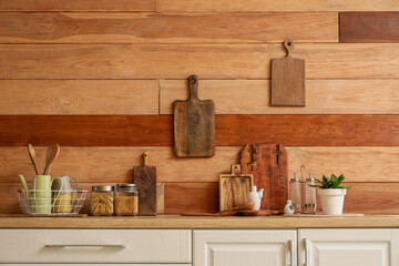 Kitchen utensils with cutting boards and food on counters near wooden wall