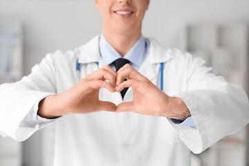 Male doctor making heart gesture in clinic, closeup