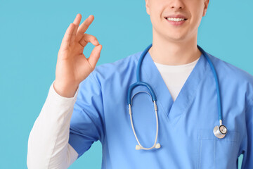 Male doctor showing OK on blue background, closeup