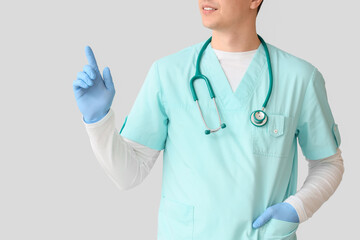 Male nurse pointing at something on light background