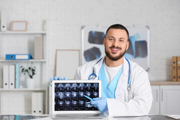Male doctor showing MRI scan of pelvis on laptop in clinic