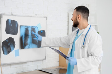 Male doctor studying x-ray scan of lungs on magnetic board in clinic