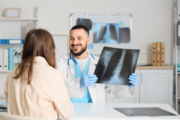 Male doctor showing x-ray scan of lungs to female patient in clinic