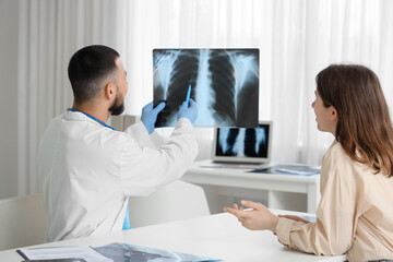 Male doctor showing x-ray scan of lungs to female patient in clinic